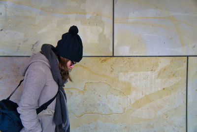 Side view of woman standing against wall