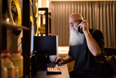 Man taking on phone while using computer at home