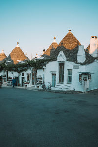 Houses by street in city against clear blue sky