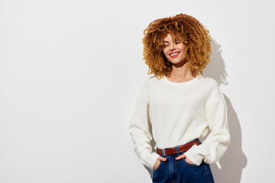 Portrait of young woman standing against white background