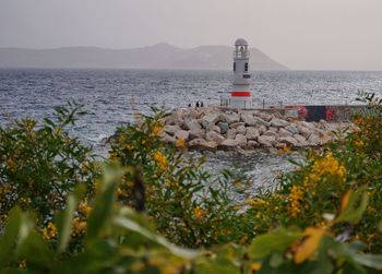 Lighthouse by sea against sky