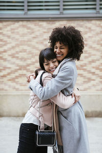 Spain, barcelona, two happy women embracing in the city