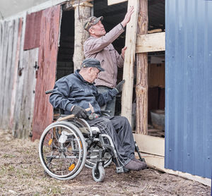 Man sitting on wood outside house