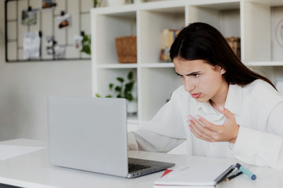 Angry young woman at home office desk work online on computer, have problems with device. unhappy