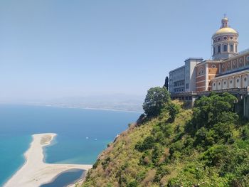 Plants growing on building by sea against clear sky