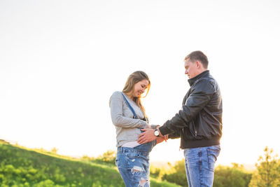 Side view of couple standing against clear sky