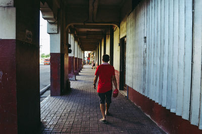 Rear view of people walking on footpath amidst buildings