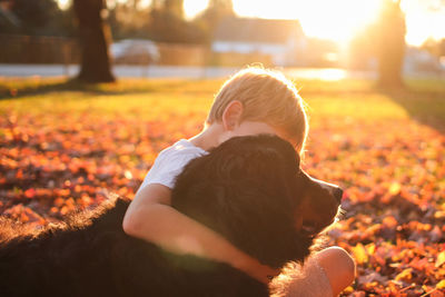 Boy sitting with dog at park during autumn