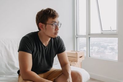 Side view of young man sitting on sofa at home