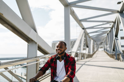 Smiling man riding bicycle on a bridge