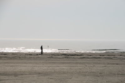 Silhouette man standing at beach against clear sky