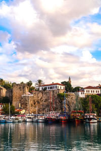 Buildings by river against sky