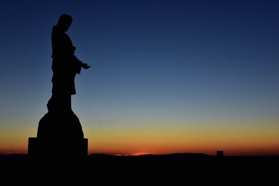 Silhouette statue against sky at sunset