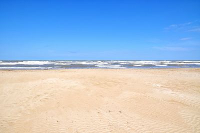 Scenic view of beach against clear blue sky