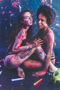 Young women wearing bikini while covered in body paint at sitting at nightclub