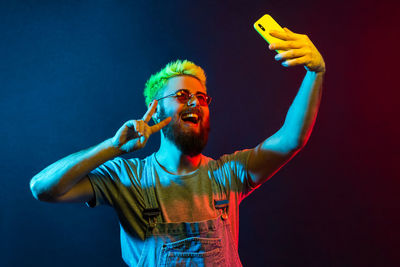 Young man with arms raised standing against gray background