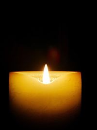 Close-up of illuminated candle in darkroom