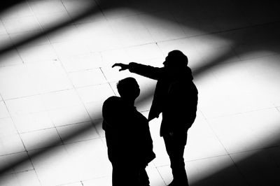 High angle view of silhouette people standing on tiled floor