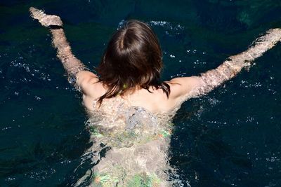 Rear view of young woman swimming in pool