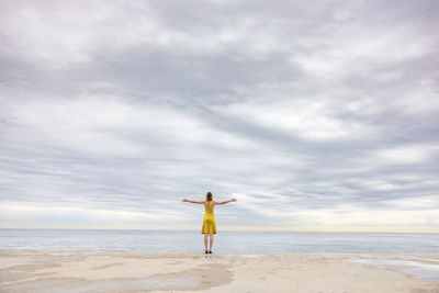 Woman with arms outstretched standing at promenade