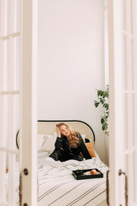 Portrait of woman sitting on window at home