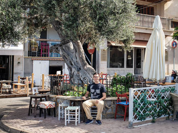 Woman sitting on chair in front of house