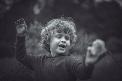 Portrait of boy with arms raised in background