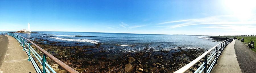 Panoramic view of road by sea against blue sky