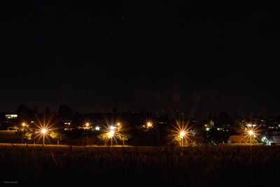 Illuminated field against sky at night