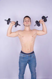 Full length of shirtless man standing against white background