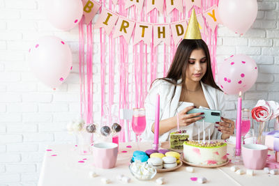 Attractive woman in white party clothes celebrating birthday taking selfie on mobile