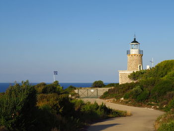 Lighthouse amidst buildings against clear blue sky