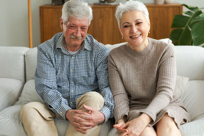 Portrait of senior couple sitting on sofa at home