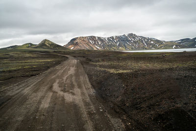 Road leading towards mountains against sky