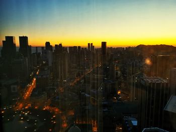 Aerial view of illuminated buildings in city against sky during sunset