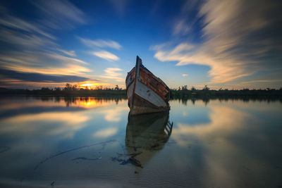 Reflection of building in lake against sky during sunset