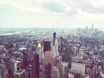 Aerial view of city buildings against cloudy sky