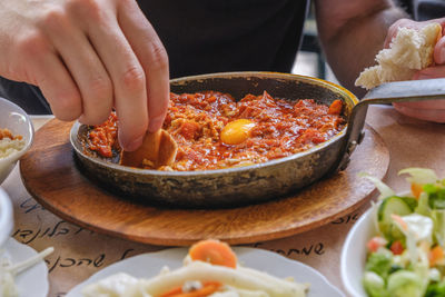 Close-up of person eating shakshouka on table
