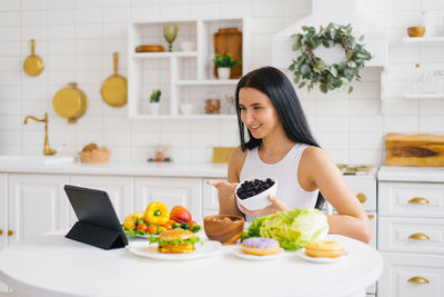 Happy woman nutritionist holds an online lesson or conference in the kitchen on the topic of healthy