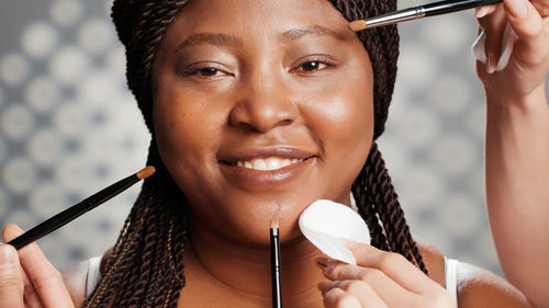 Close-up of young woman applying make-up brushes