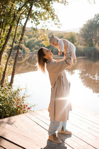 Smiling young mother playing with baby boy 1 year old wear casual clothes over nature background