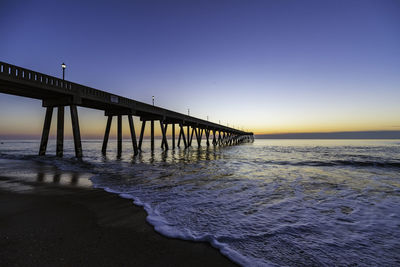 Pier over sea against clear sky during sunset