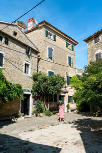 Young woman in pink dress walking in square of picturesque old town.