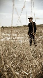 Young man standing on grassy field against sky