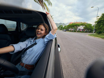 Portrait of young woman sitting on car