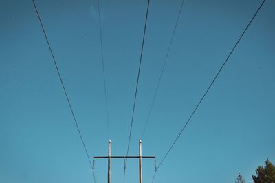 Low angle view of electricity pylon against blue sky