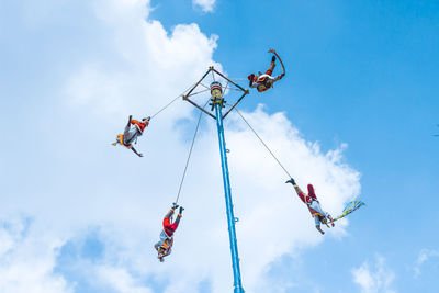 Low angle view of people paragliding against sky