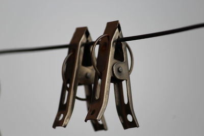 Close-up of clothespins hanging on rope against white background