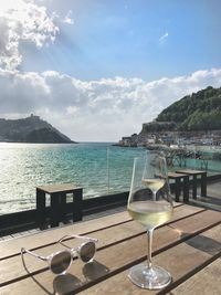 Close-up of white wine in wineglasses on table against sea