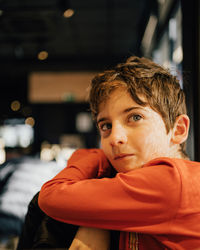 Portrait of a cute young boy looking at camera and smiling indoors low light